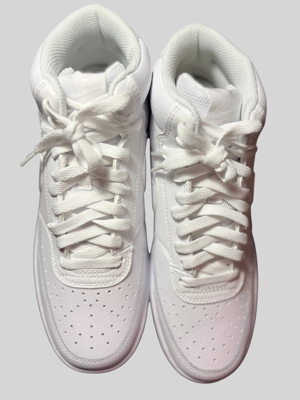 Baskets montantes Nike Court Vision Mid Triple White chez FASHION SC, en cuir blanc perforé avec lacets assortis.