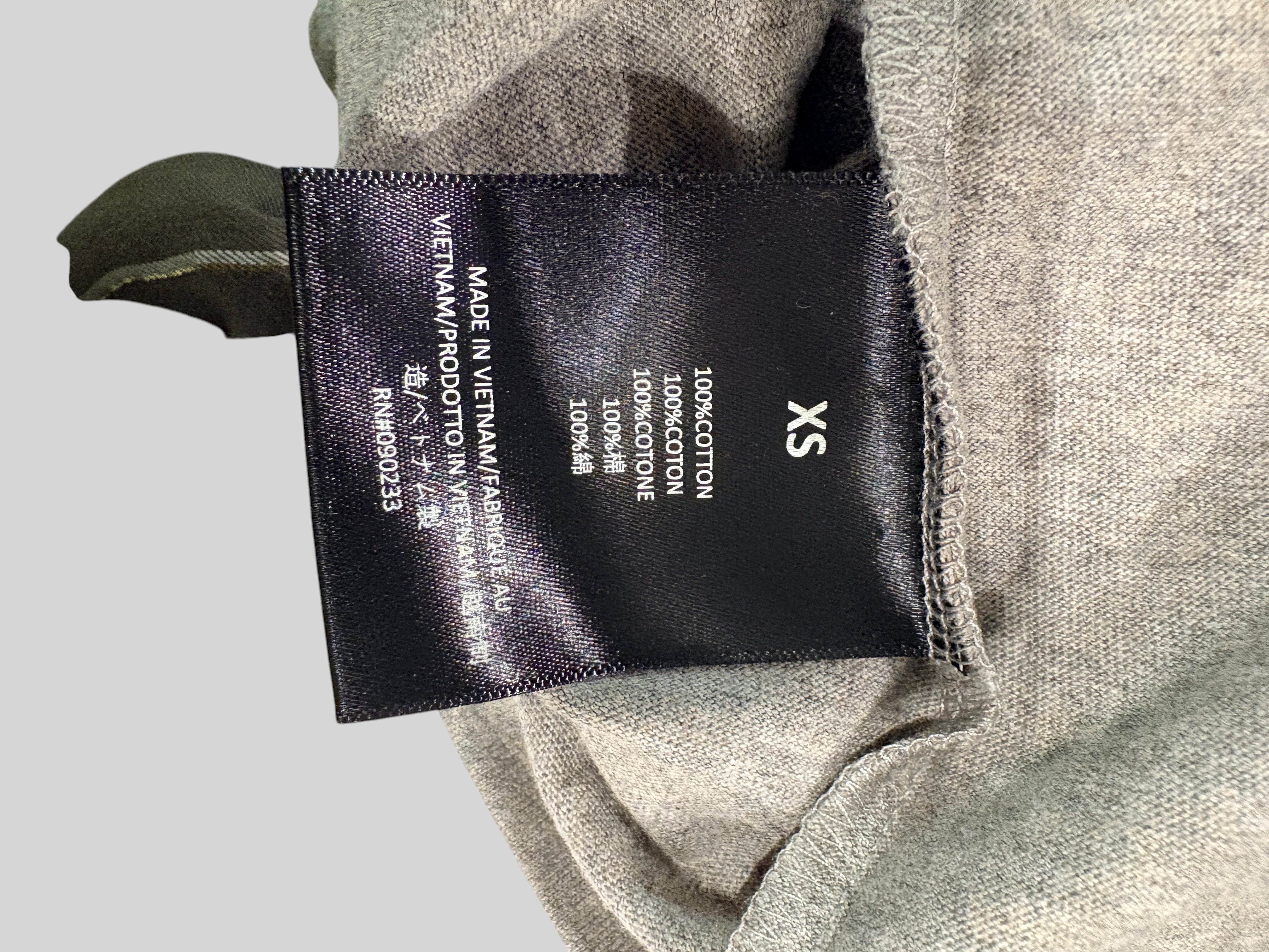 Étiquette de composition intérieure FASHION SC Fear of God Essentials indiquant 100 % coton et taille XS