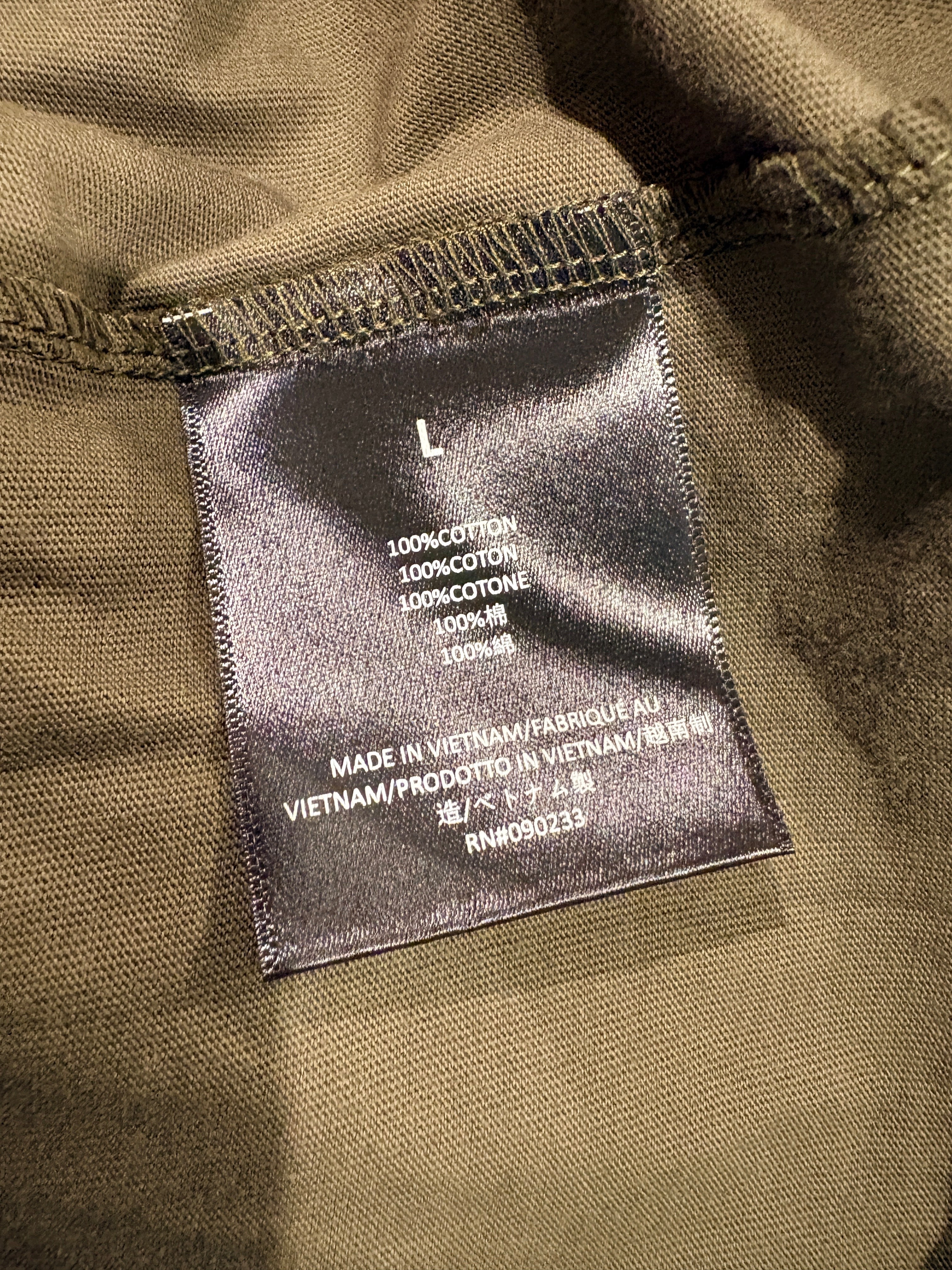 Étiquette intérieure FASHION SC Fear of God ESSENTIALS indiquant 100% coton et taille L sur tissu kaki