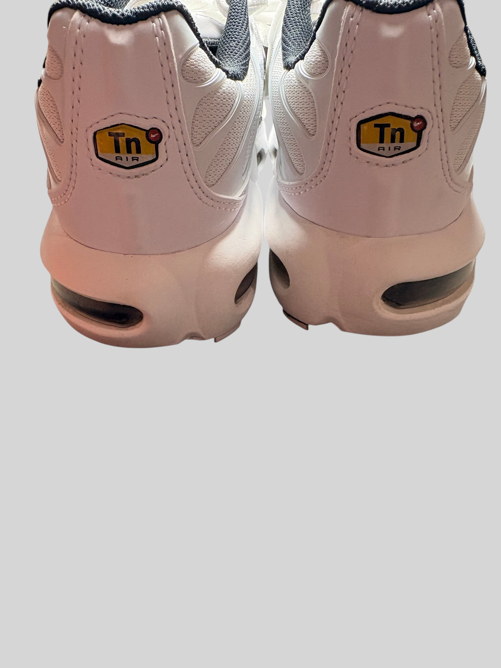 Vue arrière des baskets FASHION SC Nike Air Max Plus GS blanches et grises avec logo TN Air sur le talon