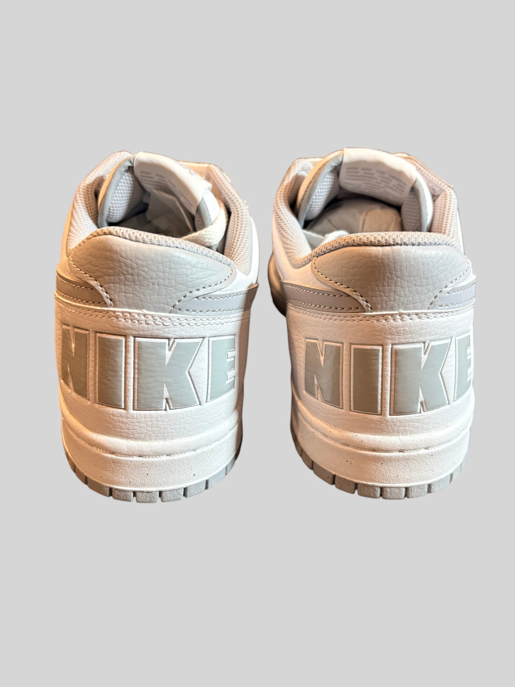 Vue arrière des baskets FASHION SC Nike Big Nike Low blanches et grises avec logo NIKE en relief sur le talon