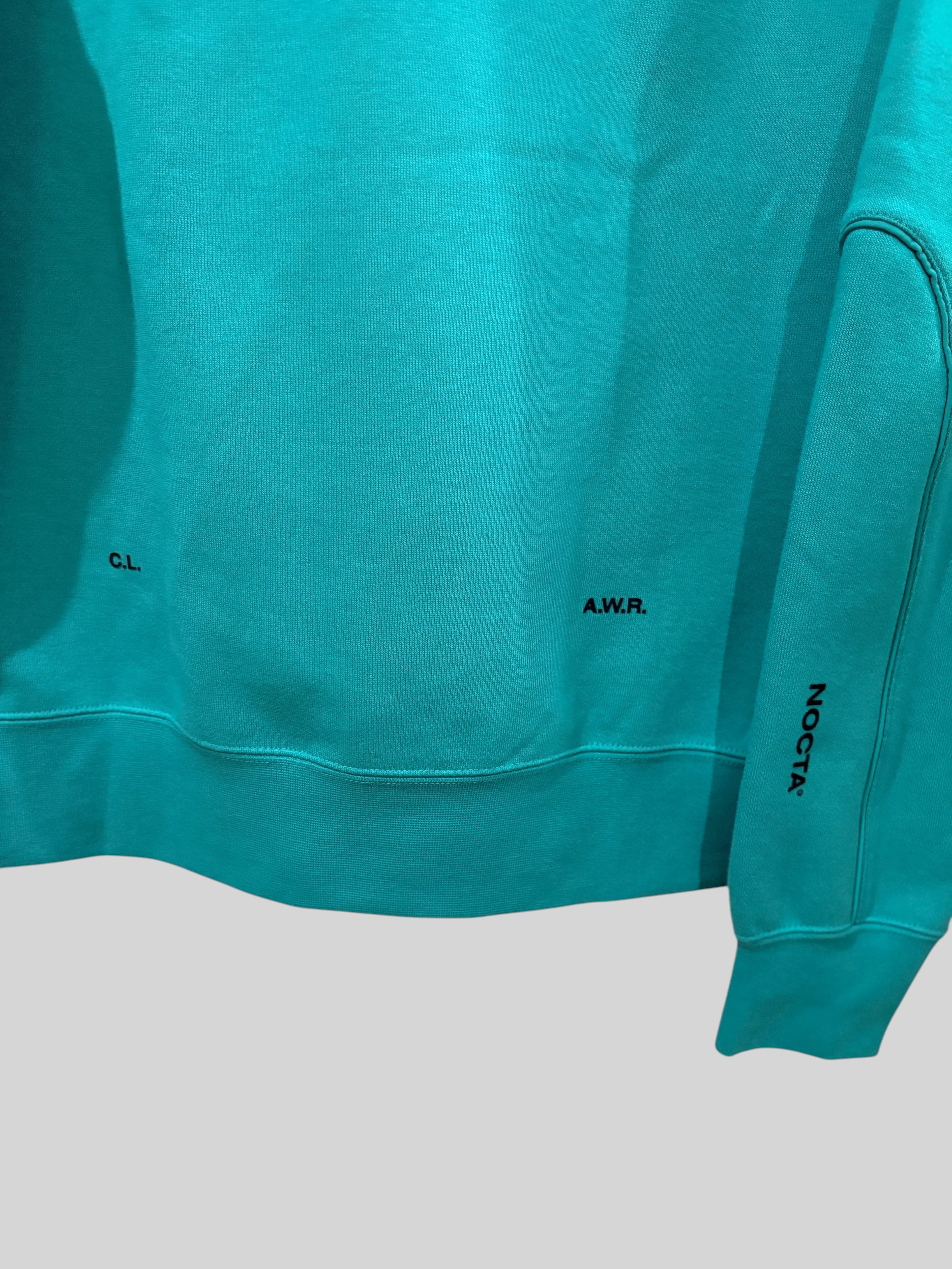 Détail du sweat FASHION SC Nike x NOCTA Fleece CS Hoodie 2 en molleton vert Neptune avec logos noirs