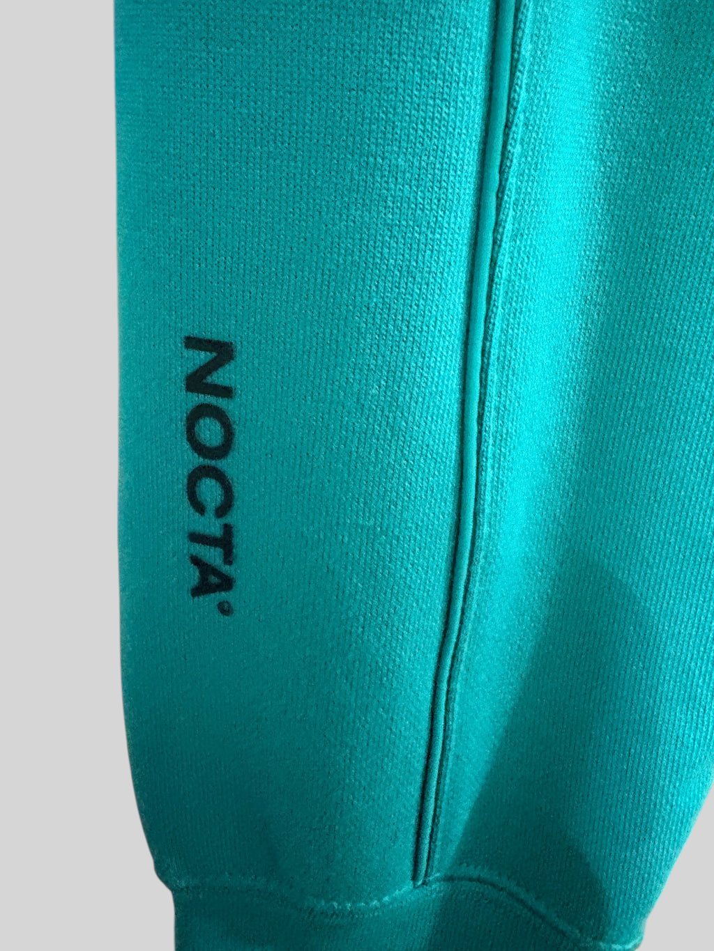 Détail du logo NOCTA noir sur le molleton vert Neptune du sweat à capuche FASHION SC Nike x NOCTA Fleece CS Hoodie 2