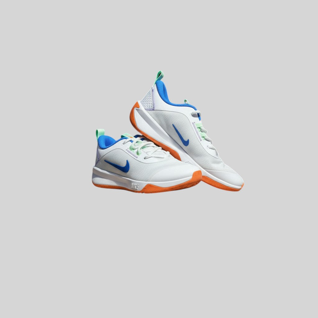 Chaussures de sport FASHION SC Nike Omni Multi-Court GS blanches avec détails bleu vif et semelle orange