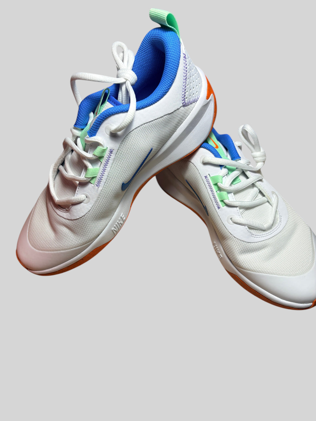Chaussures de sport FASHION SC Nike Omni Multi-Court GS blanches avec détails bleu vif, orange et vert en mesh.