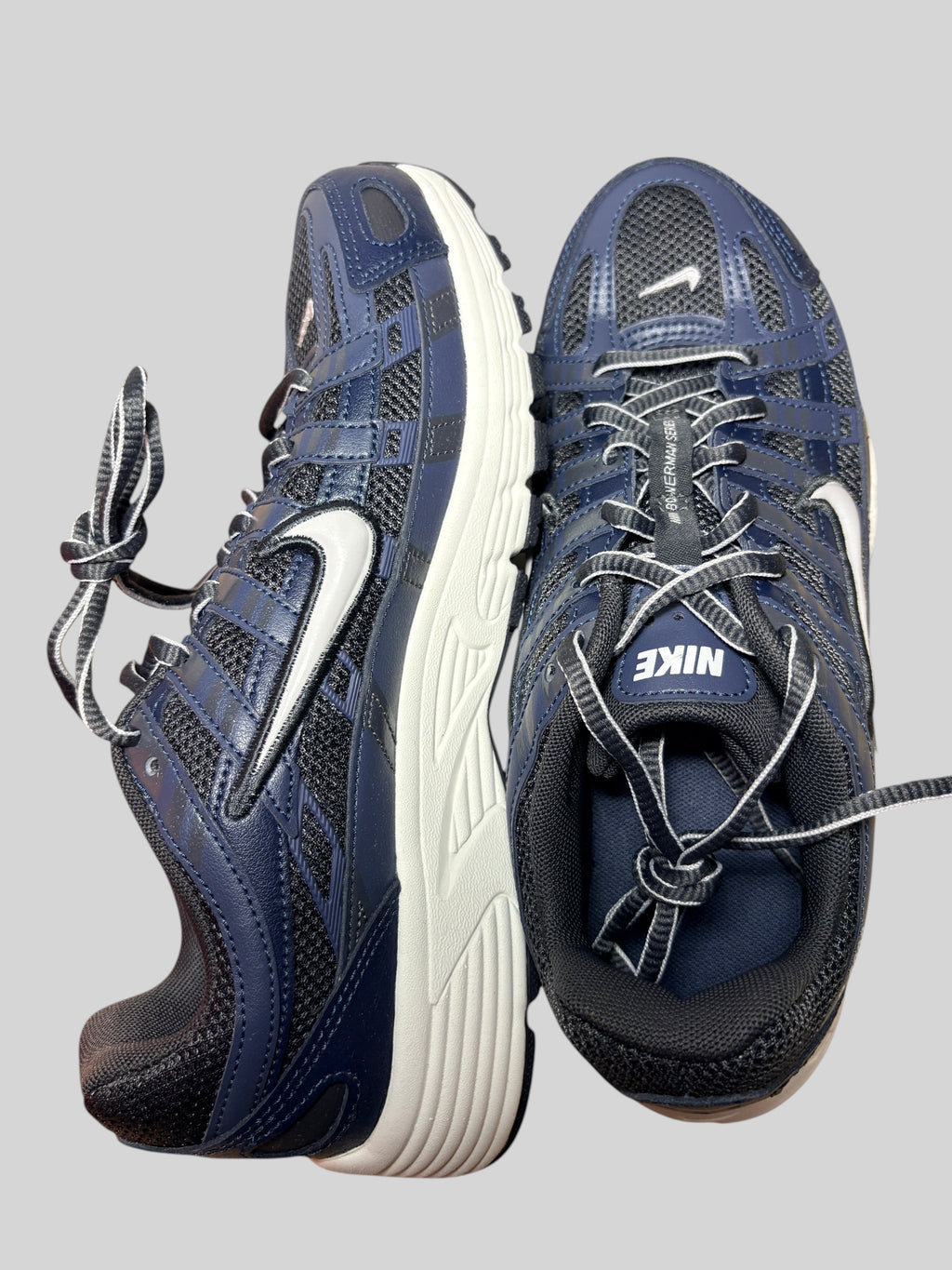 Baskets Nike P-6000 FASHION SC bleu marine et gris en cuir et mesh avec semelle blanche, style running rétro.