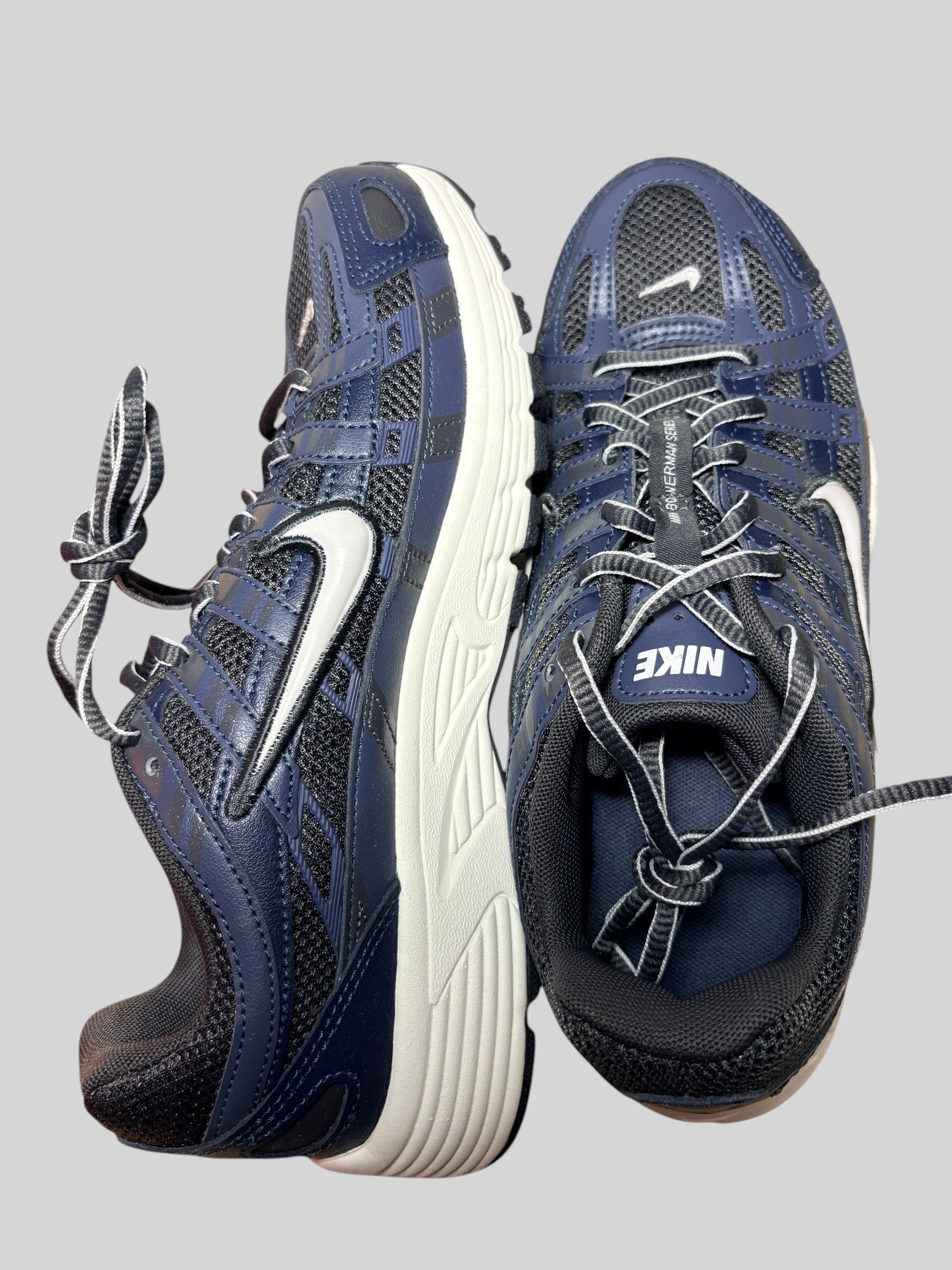 Baskets Nike P-6000 FASHION SC bleu marine et gris en cuir et mesh avec semelle blanche, style running rétro.