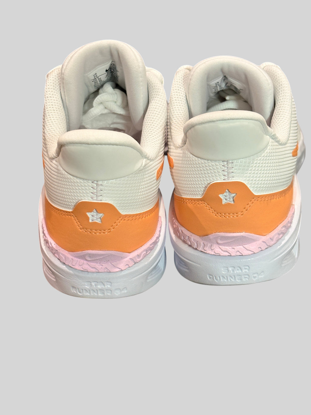 Vue arrière des baskets FASHION SC Nike Star Runner 4 NN blanches et orange avec détails en relief