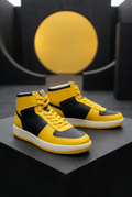 Sneakers jaunes et noires dans une mise en scène architecturale graphique